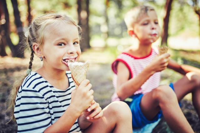 Zu einem schönen Sommerferien-Ausflug gehört auch ein Eis Mädchen und Junge essen Eis beim Ausflug
