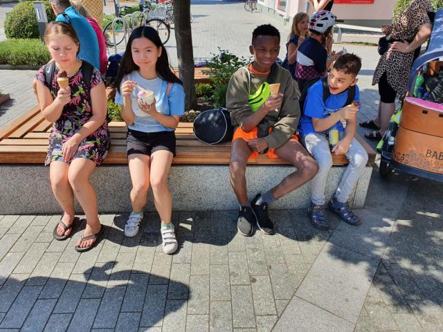 Kinder sitzen auf einer Bank und essen Eis