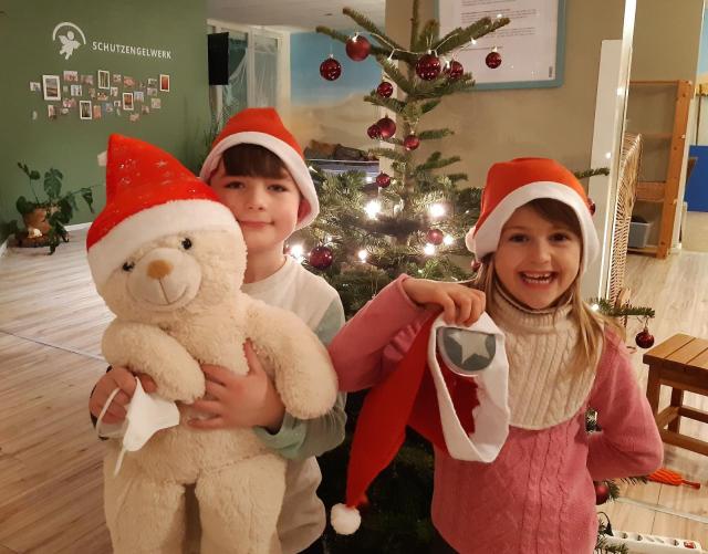 Kinder mit Weihnachtsgeschenken vor einem Tannenbaum