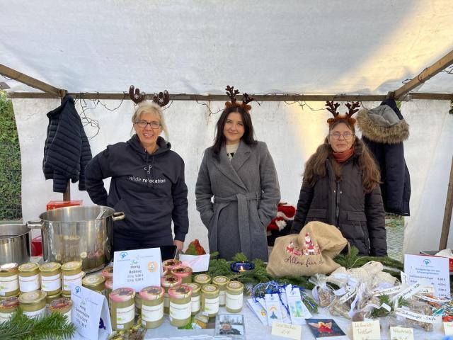 drei Frahen an einem Verkaufsstand auf einem Weihnachtsmarkt