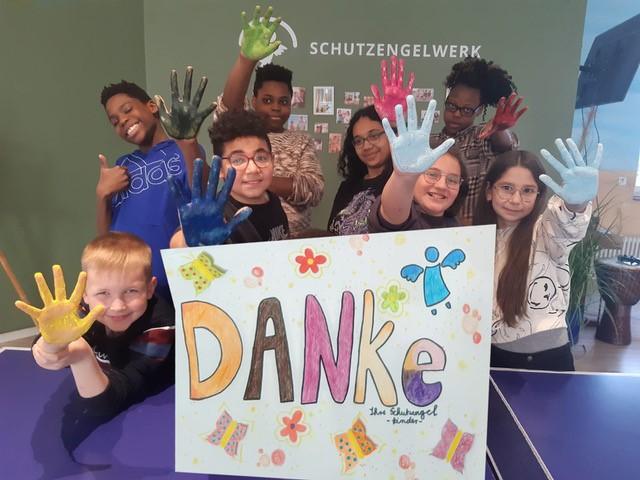 Unsere Kinder sagen DANKE Kinder mit bunten Händen halten ein Schild mit einem DANKE-Schriftzug hoch