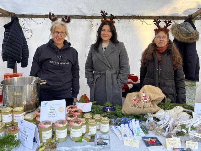 drei Frauen an einem Verkaufsstand auf einem Weihnachtsmarkt