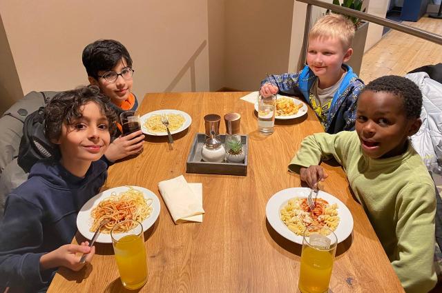 Kinder sitzen am Tisch im Erlebnisbad TURM und essen Nudeln