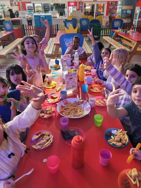 Kinder sitzen an einem bunt gedeckten Tisch beim Essen