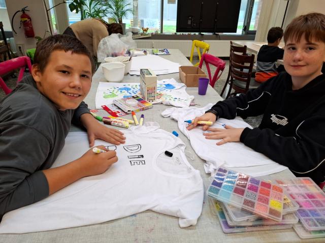 zwei Jungen bemalen ein T-Shirt mit Textilfarben