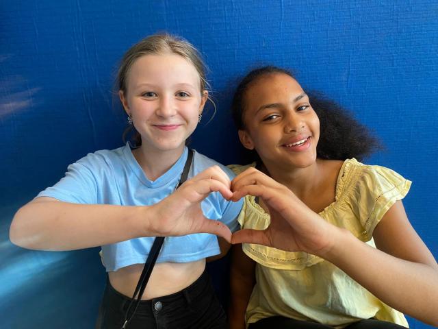 zwei Mädchen formen mit ihren Händen ein Herz