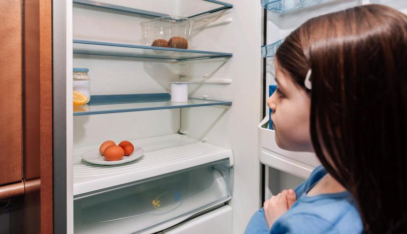 Ein leerer Kühlschrank trifft besonders die Kinder ein Mädchen steht vor einem leeren Kühlschrank