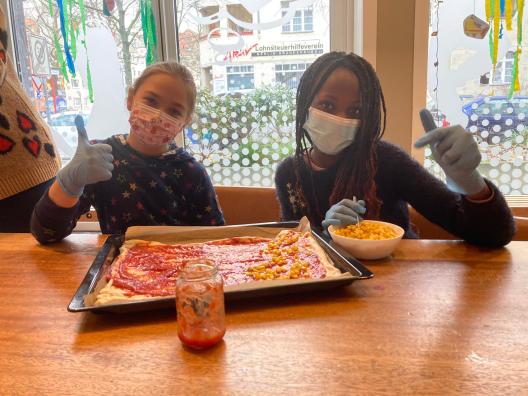 Kinder belegen eine selbstgebackene Pizza