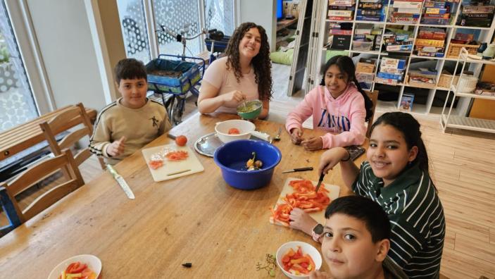 Kinder an einem großen Tisch bereiten gemeinsam ein Essen zu