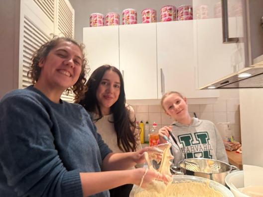 zwei Betreuer einer sozialen Einrichtung kochen zusammen mit einem Kind