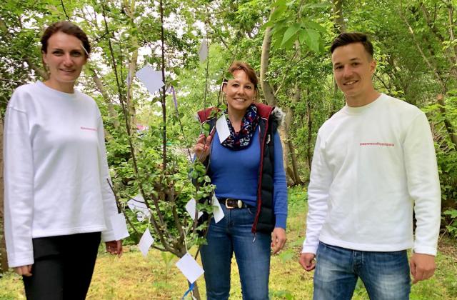 Menschen mit Kirschbaum-Setzling im Grünen.