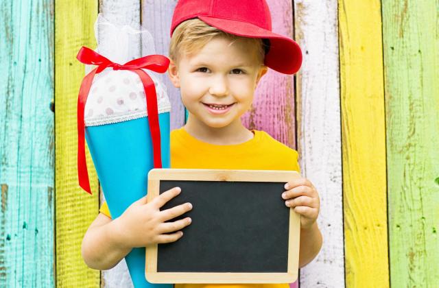 Schultütenaktion zum Schulstart 2021 Junge mit Schultüte und kleiner Tafel in der Hand