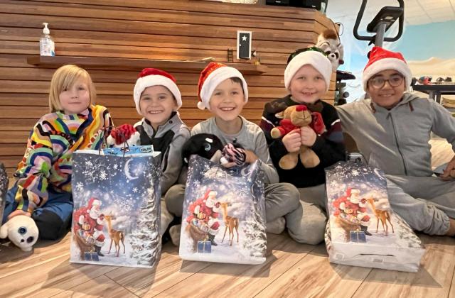 Unsere Sternenpäckchen sorgen für ein glückliches Lächeln Kinder mit Weihnachtsgeschenktüten und Kuscheltier