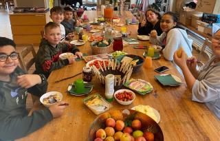 Kinder sitzen an einem gedeckten Frühstückstisch in einer sozialen Einrichtung