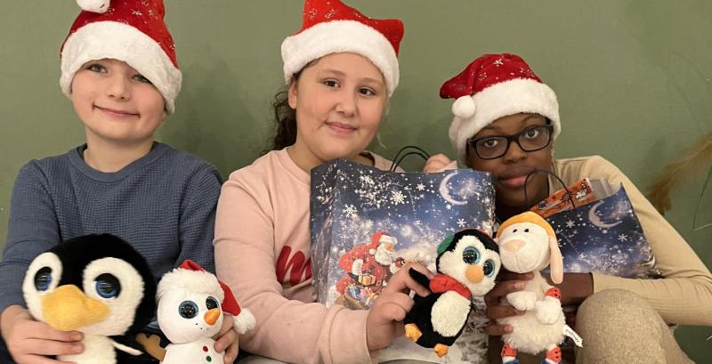 Kinder mit Weihnachtsgeschenktüten und Kuscheltier